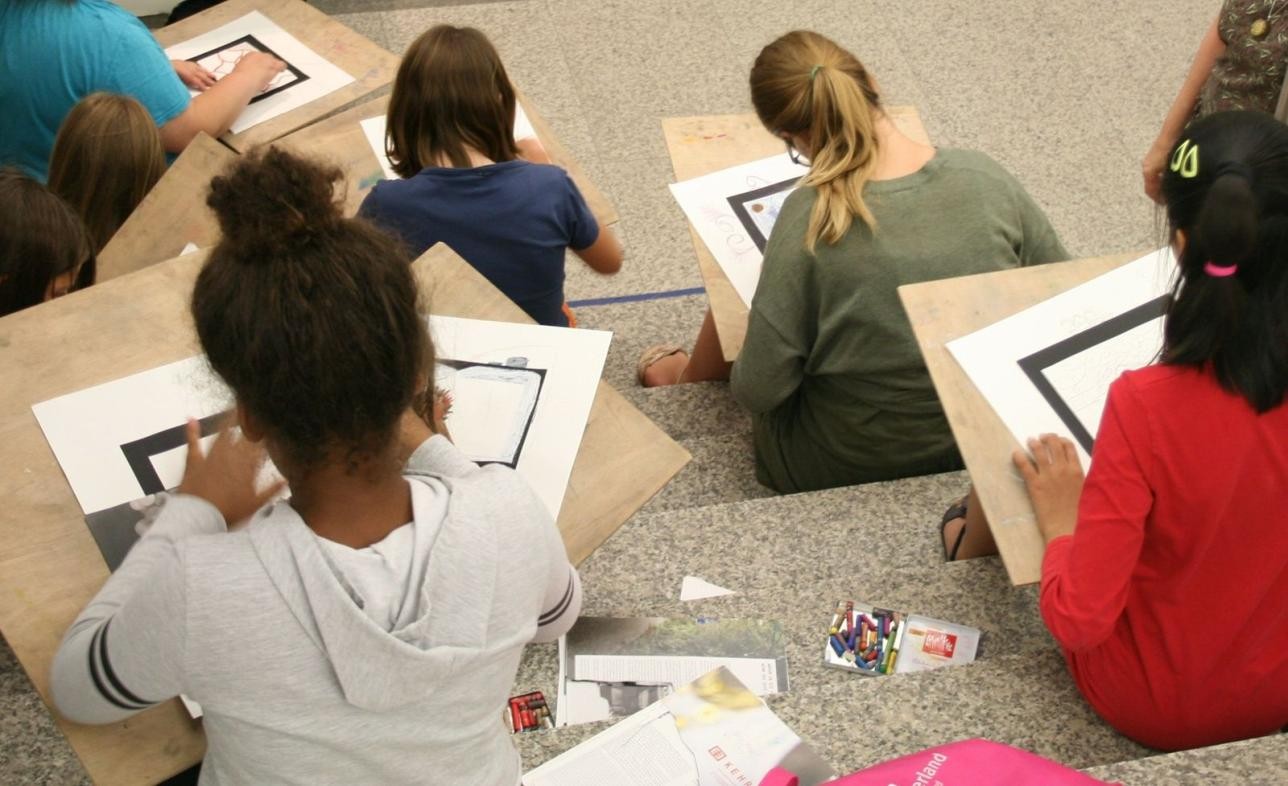 Several children sit on a staircase and draw pictures.