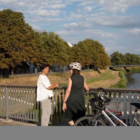 Two women on a bridge with bicycles.
