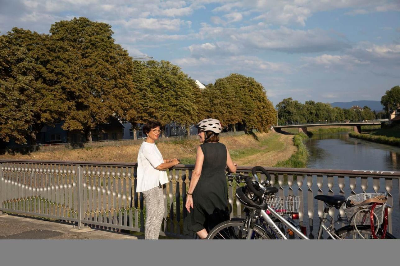 Two women on a bridge with bicycles.