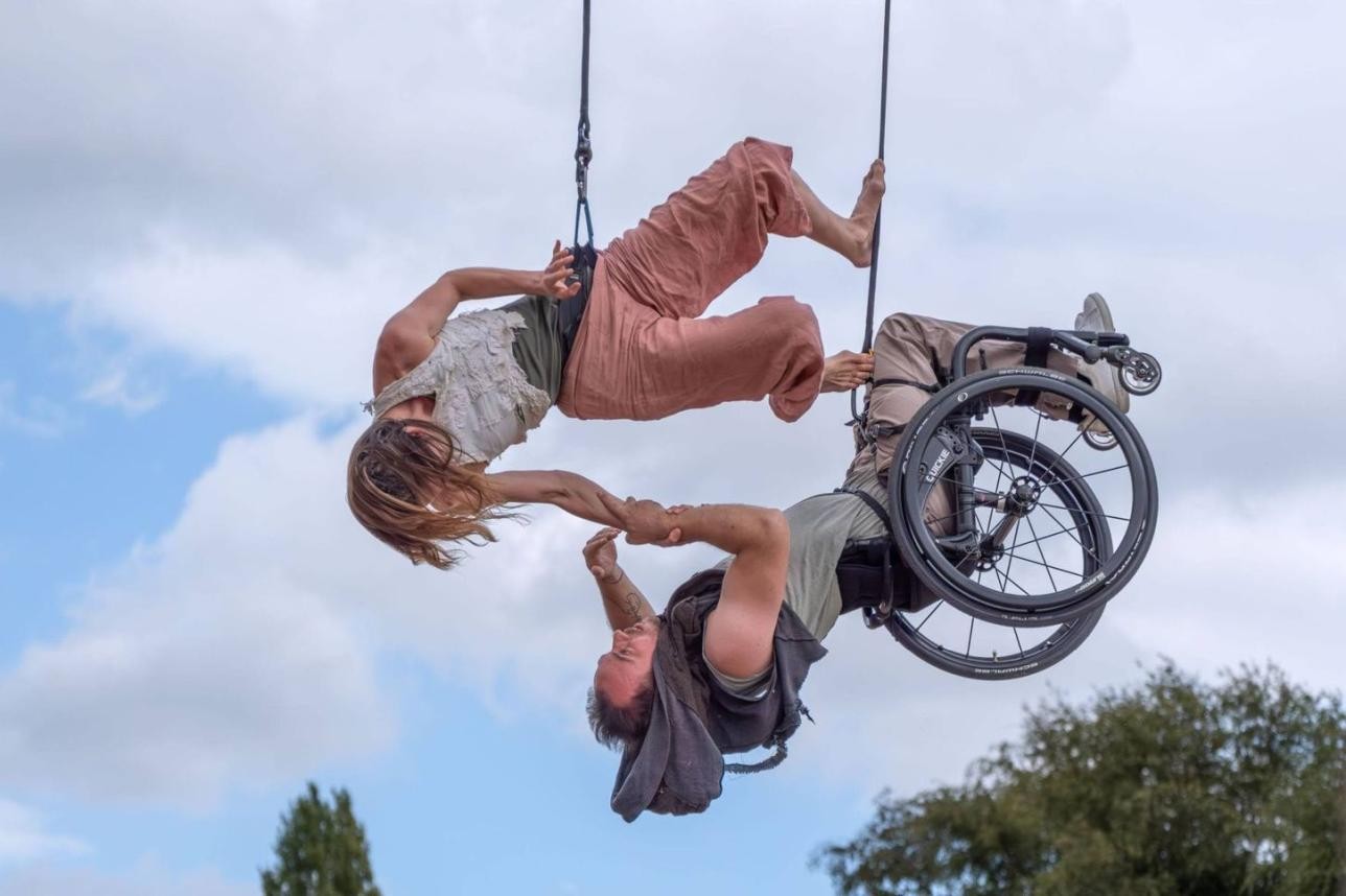 Die neuseeländische Choreografin Chloe Loftus gemeinsam mit einem Trapezartisten im Rollstuhl. Die beiden zeigen eine Performance über Gleichheit und Verbundenheit. Foto: Sander Spolspoel Die neuseeländische Choreografin Chloe Loftus gemeinsam mit einem Trapezartisten im Rollstuhl.
