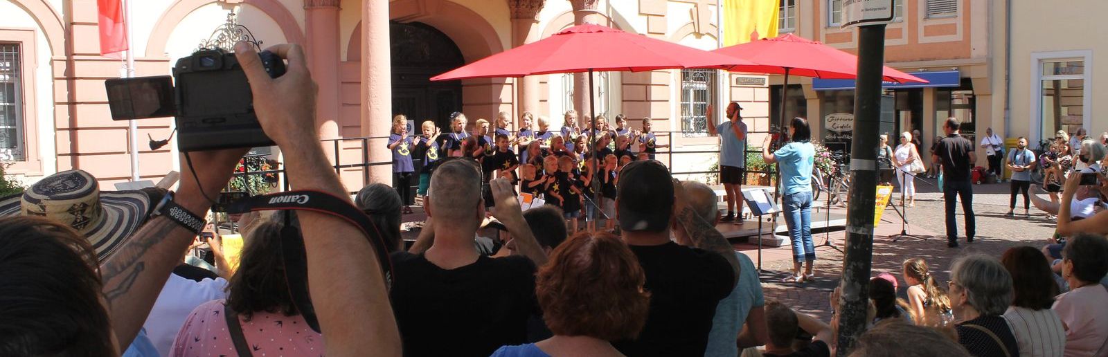 Choir sings in front of the historic town hall in Rastatt, spectators stand around in a circle